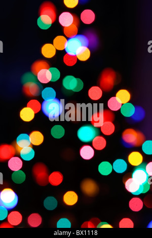 De Bokeh hors focus lumières de Noël dans la silhouette d'un arbre de Noël dans la nuit. Banque D'Images