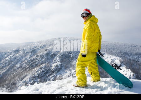 Portrait de jeune snowboarder smiling at camera en montagne Banque D'Images