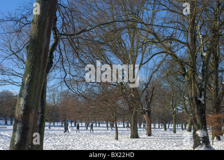 Les figures dans la neige font leur chemin à travers la prairie à Édimbourg, Écosse, Royaume-Uni. Banque D'Images