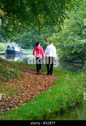 Couple marche main dans la main le long du chemin de halage du canal et du canal de l'appareil photo avec 15-04 ou péniche amarrée jusqu'en avant d'eux Banque D'Images