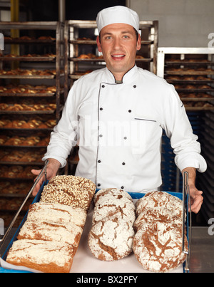 Portrait of a baker tenant un plateau avec des petits pains dans une boulangerie Banque D'Images