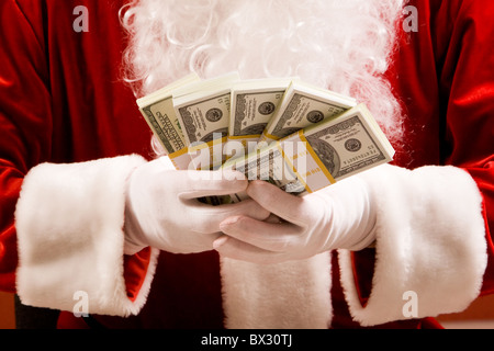 Close-up of Santa's hands avec des piles de billets en dollars Banque D'Images