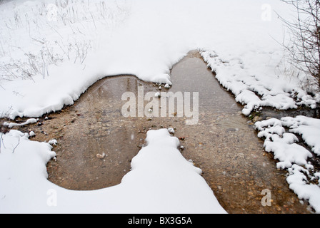 Snowy prairie traversée par petit ruisseau Banque D'Images