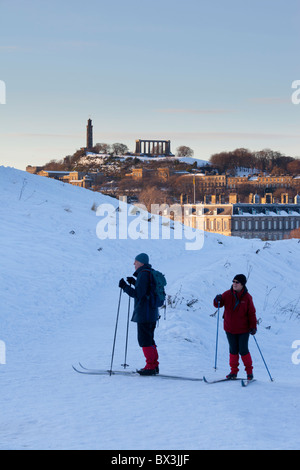 Les skieurs de fond dans le parc de Holyrood, Édimbourg, avec le palais de Holyrood et Calton Hill au coucher du soleil derrière. Banque D'Images