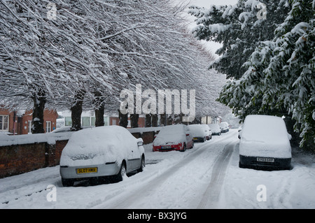 Voitures garées sur le bord de la route couverte de neige. Au début de l'hiver UK neige tomber. Banque D'Images