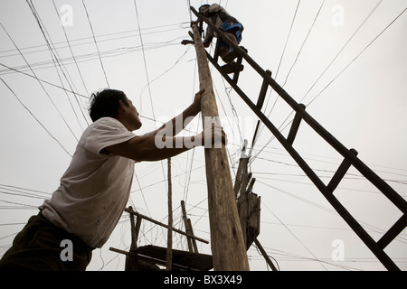 Réparation de lignes électrique hommes emmêlés dans San Juan de Miraflores, Lima, Pérou. Banque D'Images