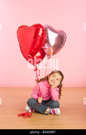 A Girl Holding Heart Shaped Balloons Banque D'Images