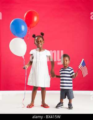 Une fille et garçon tenue rouge, blanc et bleu des ballons et un drapeau américain Banque D'Images