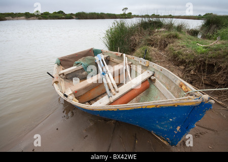 Un simple bateau de pêche avec des rames et des engins de pêche est amarré sur le bord d'une rivière Banque D'Images