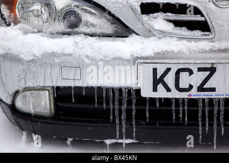 La météo, l'hiver, la glace, la neige fondante et de glaçons sur l'aile de voiture et grill. Banque D'Images