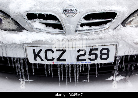 La météo, l'hiver, la glace, la neige fondante et de glaçons sur l'aile de voiture et grill. Banque D'Images