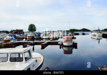 Reflets dans la mer calme des nuages et des petits bateaux ancrés dans leurs couchettes à Hollen, Kristiansand, Norvège Banque D'Images