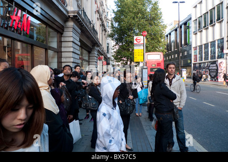 Foule multiculturelle de diversité de personnes debout en bus à Oxford Street arrêt de bus devant le magasin H&M près d'Oxford Circus London UK KATHY DEWITT Banque D'Images