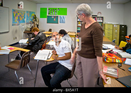 Un enseignant dans une classe d'alphabétisation de base des adultes de la communauté à San Juan Capistrano, California, encourage ses élèves dans leur travail. Banque D'Images