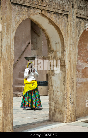 Femme indienne à marcher vers archway portant un pot ou un bol sur la tête au Fort Amber Palace, Jaipur, Rajasthan, Inde. Banque D'Images