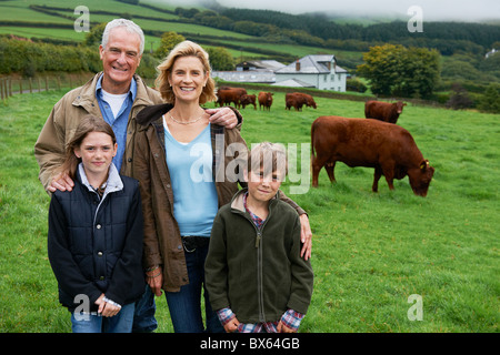 Famille dans l'exploitation dans un champ avec des vaches Banque D'Images