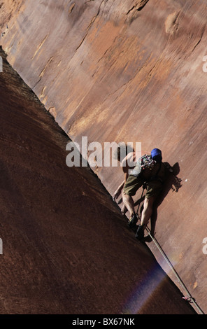 Un grimpeur s'attaque à un angle en surplomb sur les falaises de Indian Creek, un célèbre rocher d'escalade près de Moab, Utah, USA Banque D'Images