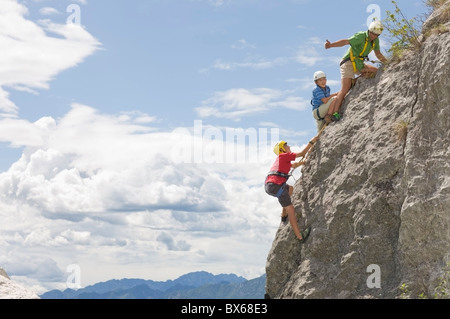 Man climbing rock avec deux garçons Banque D'Images