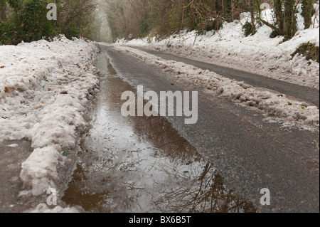 Poule et la fonte des neiges de l'écoulement dans une route de campagne causés par la neige et le temps de gel Banque D'Images