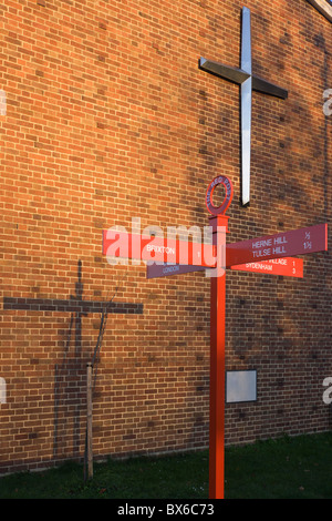 La croix sur le mur de Herne Hill's United Reform Church et la direction sign post (et son ombre) de Red poster Hill. Banque D'Images