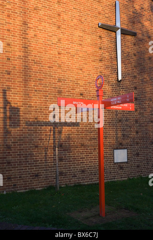 La croix sur le mur de Herne Hill's United Reform Church et la direction sign post (et son ombre) de Red poster Hill. Banque D'Images