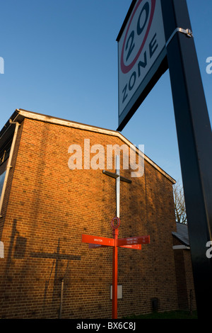 La croix sur le mur de Herne Hill's United Reform Church et la direction sign post (et son ombre) de Red poster Hill. Banque D'Images