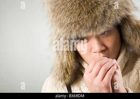 Portrait de l'homme froid au fur hat chandail tricoté et réchauffe ses mains Banque D'Images