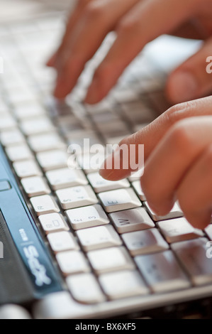 Un gros plan des doigts typing on laptop keyboard in a modern office Banque D'Images