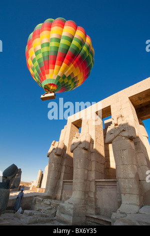 Une belle et colorée hot air balloon flotte doucement sur les statues et les ruines d'un ancien temple égyptien au lever du soleil Banque D'Images