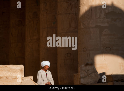 Un seul homme égyptien en costume traditionnel assis et errer dans les piliers de l'égyptien en ruine temple de Ramsès II Banque D'Images