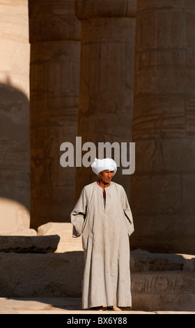 Un seul homme égyptien en costume traditionnel assis et errer dans les piliers de l'égyptien en ruine temple de Ramsès II Banque D'Images