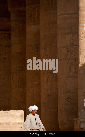 Un seul homme égyptien en costume traditionnel assis et errer dans les piliers de l'égyptien en ruine temple de Ramsès II Banque D'Images