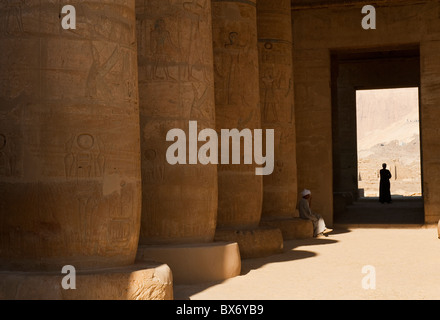 Un seul homme égyptien en costume traditionnel assis et errer dans les piliers de l'égyptien en ruine temple de Ramsès II Banque D'Images