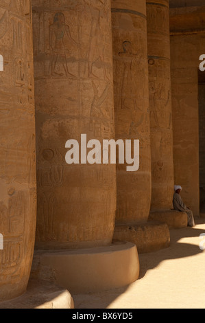 Un seul homme égyptien en costume traditionnel assis et errer dans les piliers de l'égyptien en ruine temple de Ramsès II Banque D'Images