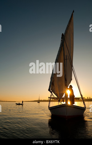 Une magnifique et belle image d'un voilier traditionnel égyptien appelé une felouque sur le Nil au coucher du soleil avec girl on board Banque D'Images