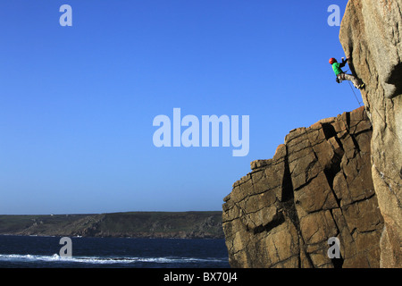 Un grimpeur aborde un itinéraire difficile sur les falaises près de Sennen Cove, un célèbre rocher d'escalade à Lands End, Cornwall, UK Banque D'Images