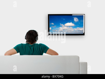 Vue arrière d'un jeune homme assis sur le canapé en regardant la télé Banque D'Images