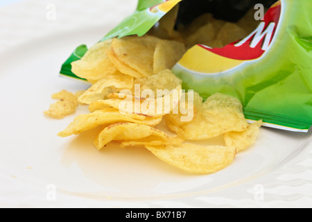 Les secoueurs ouvrent le paquet croustillant avec des chips de pomme de terre qui se répandent sur une assiette. Angleterre Royaume-Uni Banque D'Images