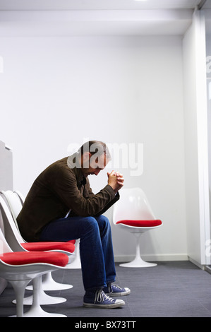 Homme assis dans sa salle d'attente du médecin Banque D'Images