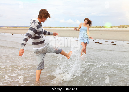 Jeune couple jouant dans les vagues Banque D'Images