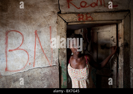 Une jeune fille se tient à la porte de son appartement d'une pièce à Monrovia, au Libéria, en Afrique de l'Ouest. Banque D'Images