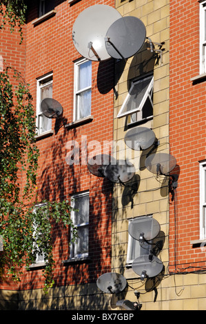 Grande grappe de télévision murale antenne satellite dish installations, y compris les antennes de télévision Sky sur le côté du bâtiment résidentiel South London England UK Banque D'Images