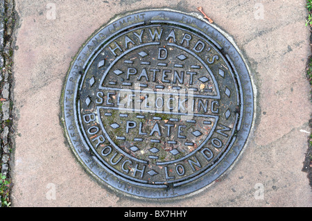 Une plaque de verrouillage auto Brevet Haywards coalhole couverture dans le sud de Londres, un trottoir. Banque D'Images