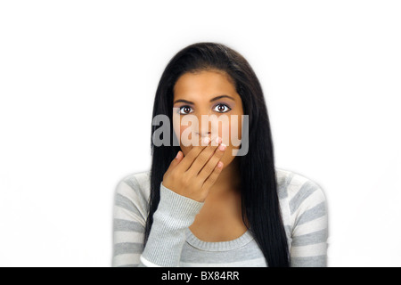 Une belle latina adolescents avec de longs cheveux noirs pulpeuse détient la main devant la bouche, apparemment choqué ou gêné. Banque D'Images