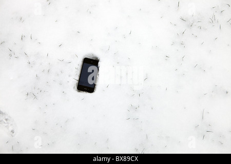 Apple Iphone portant sur le terrain dans la neige. Banque D'Images