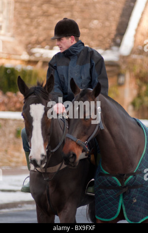 Un cavalier avec deux chevaux dans le village des Cotswolds de Broadway dans le Worcestershire, Angleterre. Banque D'Images