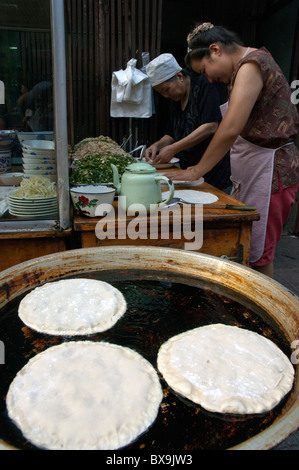 Deux femmes de la préparation des plats de crêpes à vendre à un blocage de rue dans le quartier musulman de Daqingzhen Si dans Xi'an, Shaanxi, Chine. Banque D'Images