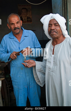 Les réparations de l'homme le bracelet de son client aux côtés d'attente, Quoseir Village, Mer Rouge, Egypte. Banque D'Images