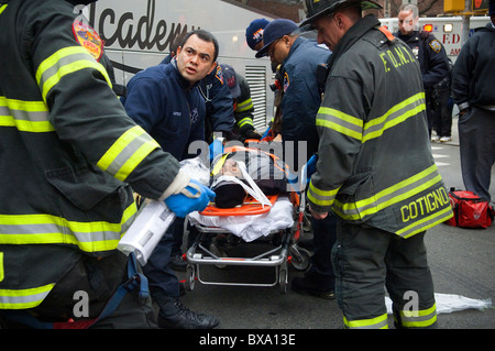 Les premiers intervenants déposer un cycliste dans une ambulance après avoir été frappé par un autobus à New York Banque D'Images