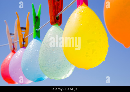 Selective focus sur un bouquet de ballons colorés avec de l'eau-gouttes d'accroché sur une corde avec un ciel bleu en arrière-plan Banque D'Images